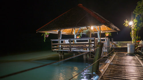 Illuminated pier over lake against sky at night