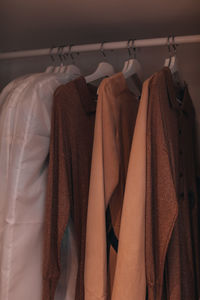Clothes in beige and brown autumn colors hanging on a hanger in the closet