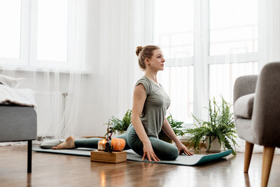 Beautiful young woman doing exercises and doing yoga at home