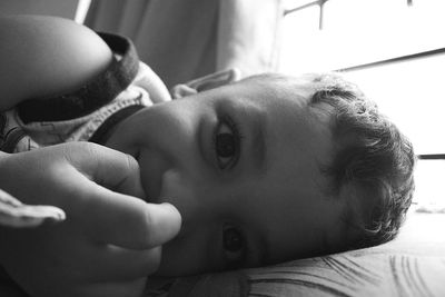 Close-up portrait of cute girl lying on bed at home