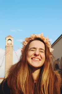 Portrait of young woman wearing sunglasses while standing against blue sky