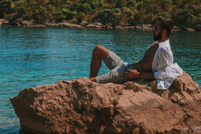 Man sitting on rock looking at sea