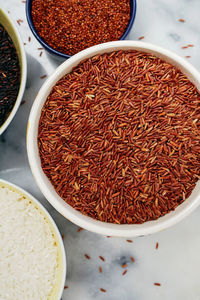 Ceramic bowls filled with a variety of grain and rice including red quinoa, red and white rice