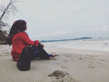 Side view of woman sitting on beach