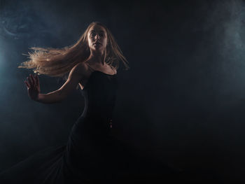 Woman dancing against black background