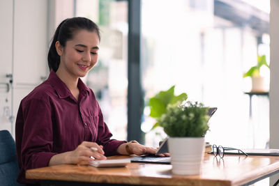 Portrait of young woman using phone while sitting on table