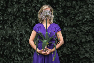 Midsection of woman standing by purple flowering plants