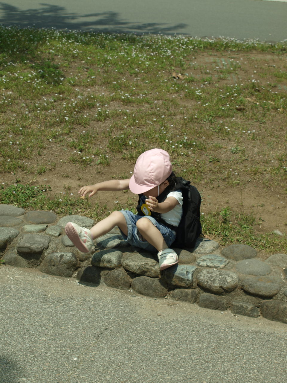 HIGH ANGLE VIEW OF WOMAN SITTING ON LAND BY ROAD