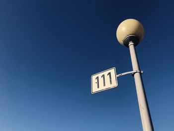 Low angle view of information sign against clear blue sky