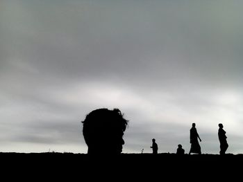 Silhouette people standing on field against sky