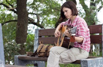 Low angle view of woman playing guitar in park