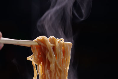 Close-up of person holding ice cream against black background