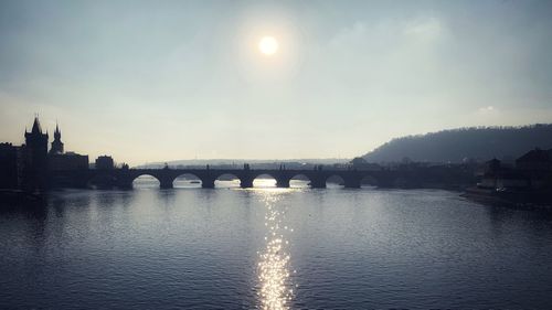 Arch bridge over river against sky in city