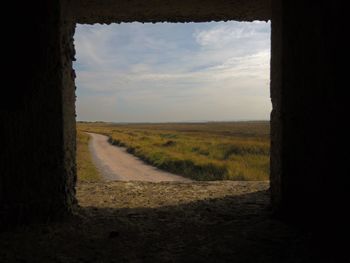 Road amidst field against sky