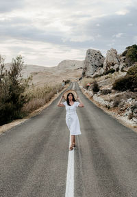 Woman standing on road against sky