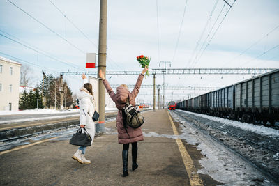Two girls at the station happily with flowers meet the train