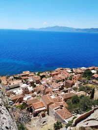 High angle view of townscape by sea against blue sky