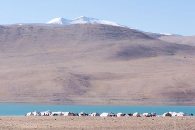 Scenic view of sea by mountains against clear sky