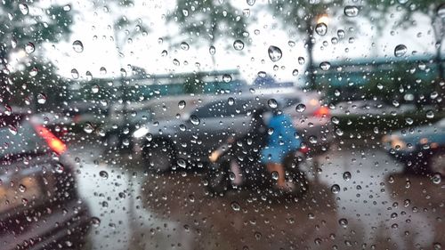 Cars on road seen through wet window during rainy season