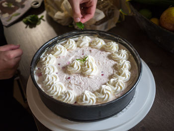 Human hands decorating cream pie with mint leaves