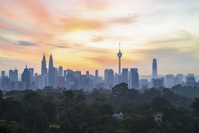 Modern buildings in city against sky during sunset