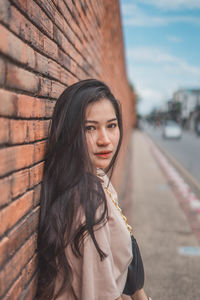 Portrait of smiling woman standing against brick wall