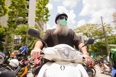 Rear view of man riding motor scooter on street