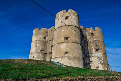 Low angle view of old building against blue sky