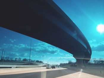 Road by bridge against blue sky