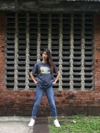 Portrait of a smiling young woman standing against brick wall