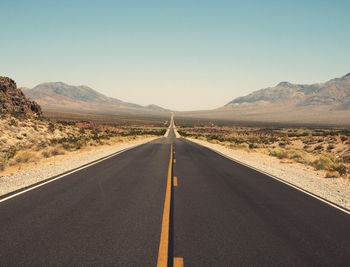 Empty road along landscape and mountains against sky