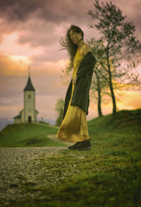 Woman in yellow dress observing a church in the distance, slovenia ii
