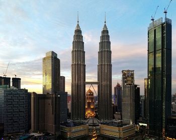 Low angle view of skyscrapers against cloudy sky