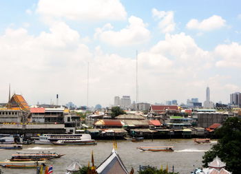 Sailboats moored at harbor by buildings in city against sky