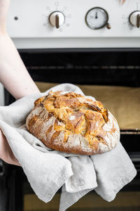 Cropped hands of woman holding bread at kitchen