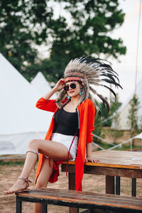 Portrait of young woman wearing headdress while sitting on picnic table