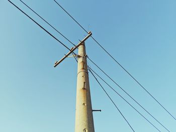 Low angle view of electricity pylon against clear sky