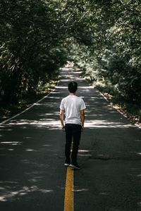 Rear view of man walking on road