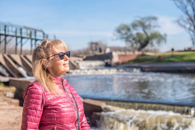 Cropped view of a cheerful adult woman looking away with sunglasses standing in the park