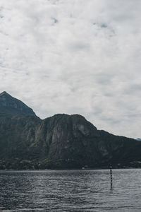 Scenic view of sea and mountains against cloudy sky