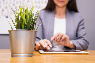 Midsection of woman using digital tablet at desk