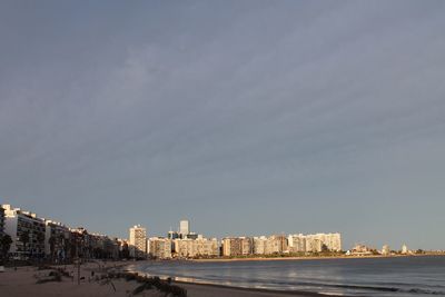 Sea by buildings against sky in city