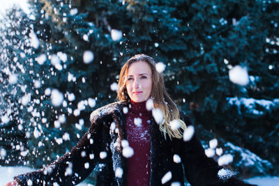 Smiling woman throwing snow outdoors during winter
