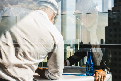 Side view of man using mobile phone while standing on table