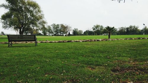 Park bench on field against sky