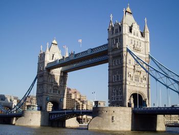 Tower bridge over thames river against clear blue sky