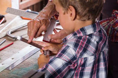 High angle view of man teaching boy carpentry on workbench