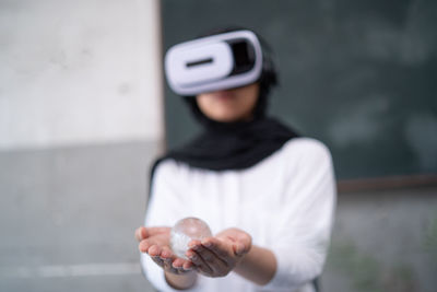 Woman wearing virtual reality simulator while holding crystal ball