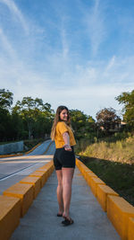 Full length of woman standing on road against trees