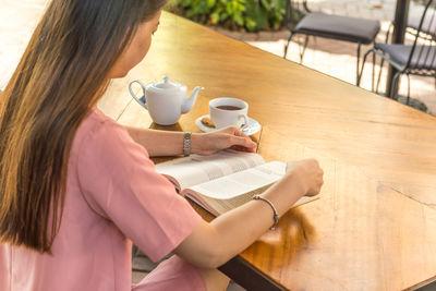 Rear view of young woman reading book